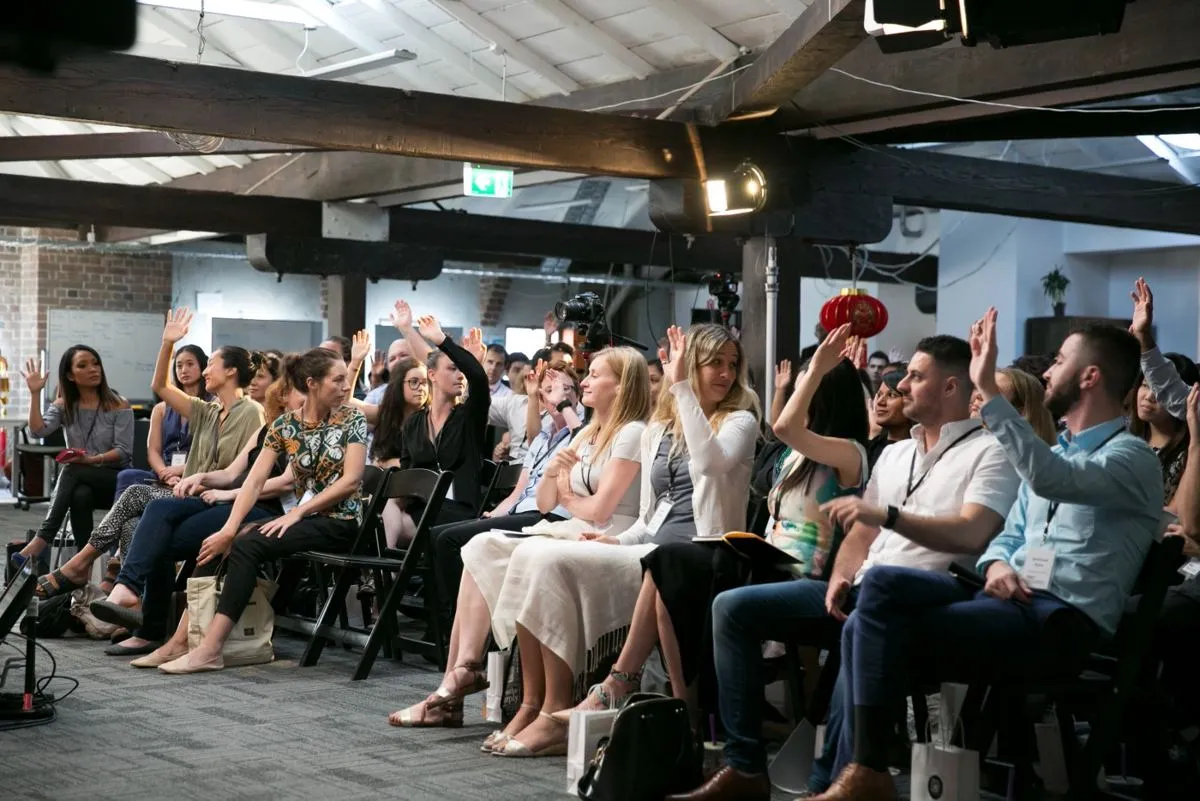 Audience members raising their hands at an HHQ workshop
